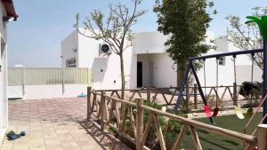 une maison avec une clôture et une aire de jeux dans l'établissement Palm House, à Nizwa