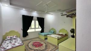 une chambre avec deux lits et une fenêtre dans l'établissement Palm House, à Nizwa