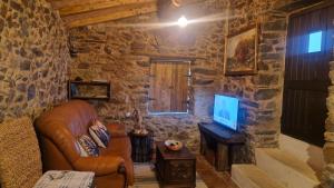 Una sala de estar con un sofá de cuero y un televisor. en Casa do Forno, en Miranda do Corvo