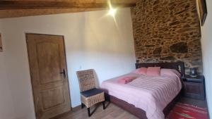 Un dormitorio con una cama y una silla y una puerta. en Casa do Forno, en Miranda do Corvo