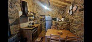 Una cocina con una mesa de madera y un refrigerador. en Casa do Forno, en Miranda do Corvo