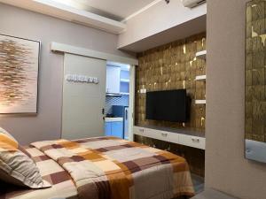 a bedroom with a bed and a flat screen tv at Modern 2BR Apartment Anderson Pakuwon Mall in Surabaya
