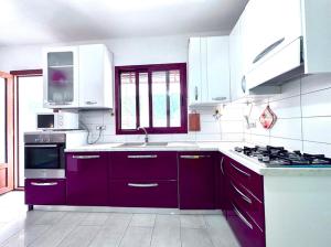 a kitchen with purple cabinets and a stove at Villa Julien Quartu Sant'Elena Sardegna in Santa Luria