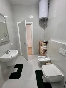 une salle de bain blanche avec un lavabo et des toilettes dans l'établissement Kino Apartment, à Tirana 5 autres photos
