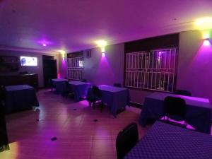 a room with purple lighting and tables and chairs at Panda hotel in Entebbe