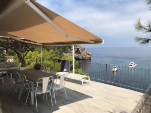 a patio with a table and chairs and a view of the ocean at VILLA CA LA DOLORS Cala Deià in Deia
