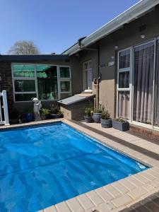 a blue swimming pool in front of a house at 15 On Palm East in Edenvale