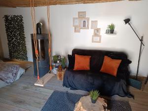 a living room with a black couch with orange pillows at Cabane cozzi dépendance à la ferme avec jacuzzi in Plouzané