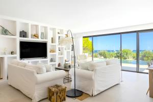a living room with two white chairs and a tv at Villa San Ciprianu Mare Di Lecci in Lecci