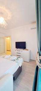 a white bedroom with a bed and a television at Relax Home apartments in Iaşi
