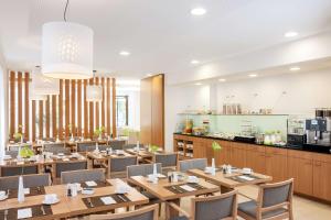a restaurant with wooden tables and chairs and a kitchen at NH Frankfurt Messe in Frankfurt/Main