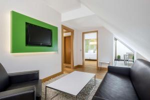 a living room with a couch and a tv on a wall at NH Frankfurt Messe in Frankfurt +26 photos