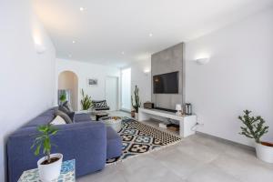 a living room with a blue couch and a tv at Casa da Praça - Vila do Bispo, Algarve in Vila do Bispo