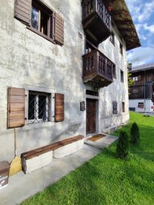 Un edificio antiguo con ventanas de madera y balcón. en Alma Hunting Lodge, en Borca di Cadore