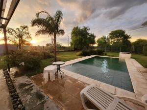 a pool with two chairs and a table and a palm tree at Arbol in Sauce Bajada