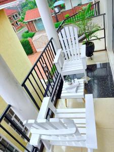 un par de sillas blancas sentadas en un balcón en kigali Pillar House inn, en Kigali