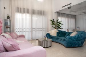 a living room with two blue couches and a plant at Chill Villa - וילה מהממת עם בריכה פרטית מחוממת in Ashkelon