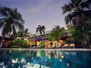a swimming pool in front of a house with palm trees at Spacieuse villa avec piscine privée à Saint-Gilles les Bains 300 m² in Grand Fond
