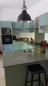 a kitchen with a sink and a black stool at Spacieuse villa avec piscine privée à Saint-Gilles les Bains 300 m² in Grand Fond +5 photos
