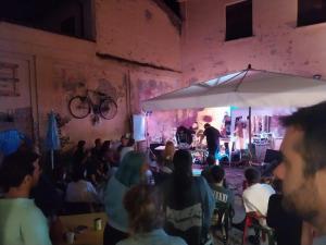a crowd of people sitting in a room with a stage at Arci Isola Ostello Sociale in Imola
