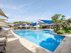 a swimming pool with blue water in a resort at Beachside Getaway - Family Villa at Sebel Resort in Broadwater