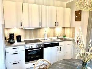 a kitchen with white cabinets and a sink and a table at Ostfresenstuv in Neßmersiel