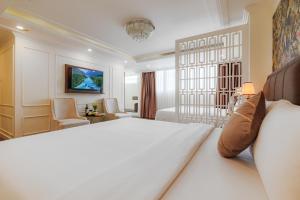 ホーチミン・シティにあるElite SOFEA Saigon Hotel and Spaの大きなベッドとリビングルームがあるホテルの部屋