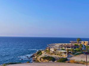 una casa grande en una colina junto al océano en Wake Up by the Sea Oceanfront Garden Retreat with Pool, en Küçükerenköy