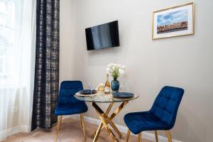 a dining room with a table and two blue chairs at Amethyst Apartments - Csepreghy in Budapest