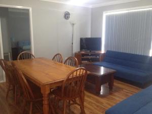 a living room with a wooden table and a blue couch at Green Meadow in Nowra