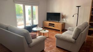 een woonkamer met 2 stoelen en een flatscreen-tv bij Casa Biamar in Calpe