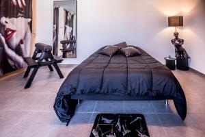 a bedroom with a bed and a chair in it at PRoJET KUROI - Love Room BDSM - Balançoire, Banc de fessée, Cage, Croix, Tantra in Walbourg