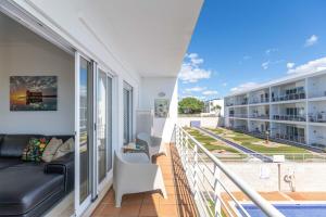 a balcony with a couch and chairs on a building at Apartment Calma, Formosa Village in Fuzeta