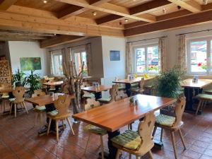 a restaurant with wooden tables and chairs and windows at Hotel Chalamandrin in Ftan