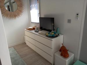 een slaapkamer met een dressoir met een tv en een spiegel bij Entre mer et golf in Moliets-et-Maa