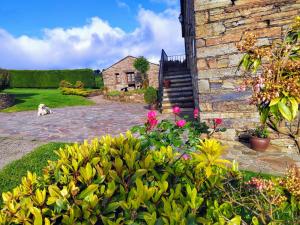 a dog sitting next to a brick building with flowers at Pajar in Braña