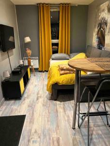 a bedroom with a bed and a table and yellow curtains at Studio tres confortable en centre ville in Hénin-Beaumont