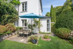 a garden with a table and a blue umbrella at Ferienwohnungen Benzenberg in Tutzing