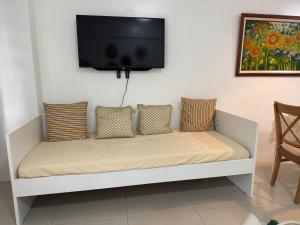 um sofá branco com almofadas e uma televisão na parede em Telly's Studio Across NAIA3 em Manilla