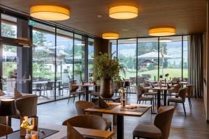 a restaurant with tables and chairs and large windows at Berg & Golf Apartments Westendorf by ALPS RESORTS in Westendorf