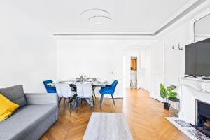 sala de estar con sofá gris, mesa y sillas en Arc de Triomphe - Luxurious 3 Bedroom with NetFlix, en París