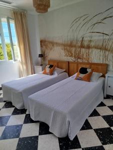 two beds in a bedroom with a checkered floor at Villa climatisée, proche mer, 2 grands appartements indépendants, parking, WIFI in Le Grau-dʼAgde