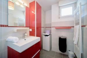 a bathroom with a white sink and red cabinets at Bright, 2 bedrooms, central, garage and balcony in Condrieu +7 photos