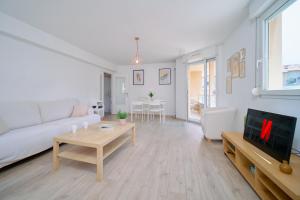 a living room with a white couch and a table at Bright, 2 bedrooms, central, garage and balcony in Condrieu