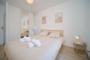 a white bedroom with a large bed with white pillows at Bright, 2 bedrooms, central, garage and balcony in Condrieu