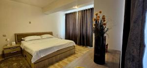 1 dormitorio con 1 cama y un jarrón con flores en Loft Craiova Apartament, en Craiova