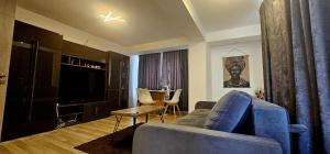 Una sala de estar con un sofá azul y un televisor. en Loft Craiova Apartament, en Craiova