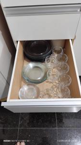 a drawer with plates and glasses in a kitchen at Apartamento São Pedro da Aldeia frente para lagoa in São Pedro da Aldeia