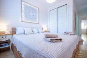 ein weißes Schlafzimmer mit einem Bett mit Handtüchern darauf in der Unterkunft Le Solarium Campoamor in Orihuela + 16 Fotos