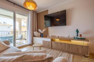 ein Wohnzimmer mit einem Sofa und einem Fernseher an der Wand in der Unterkunft Le Solarium Campoamor in Orihuela
